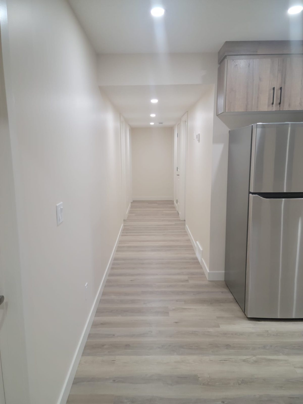 Basement suite hallway leading past the kitchen with pot lighting